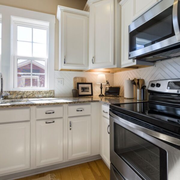 Clean modern kitchen with white cabinets and stainless appliances