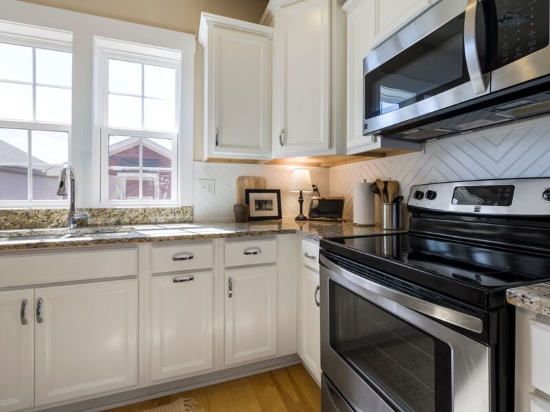 Clean modern kitchen with white cabinets and stainless appliances