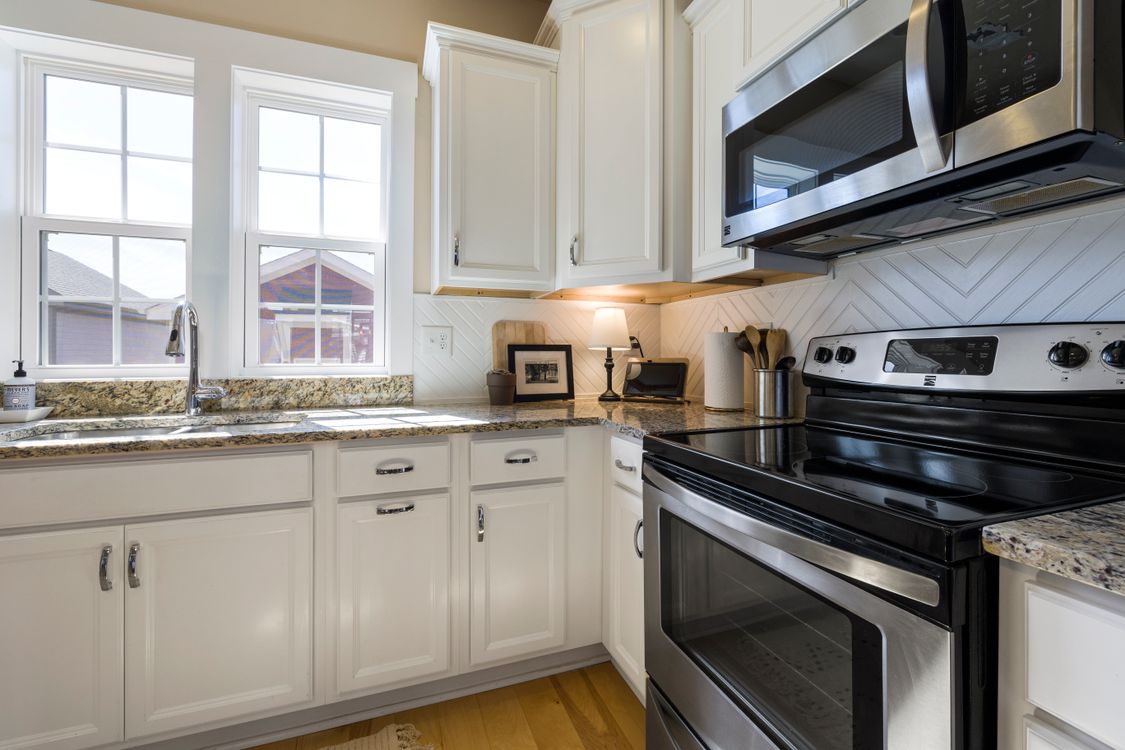 Clean modern kitchen with white cabinets and stainless appliances